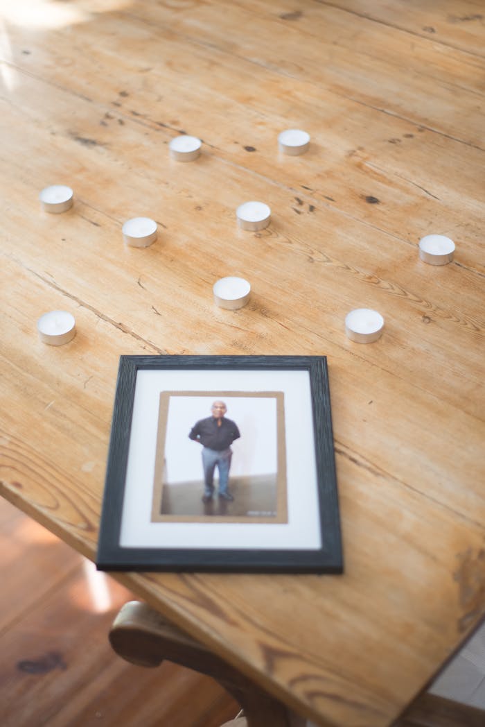 Framed photo with candles on wooden table symbolizing remembrance and loss.